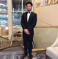 a man in a tuxedo standing in front of a staircase